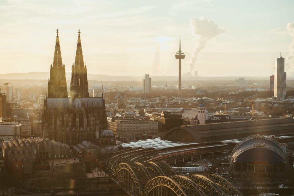 A breathtaking view of Cologne Cathedral at sunrise, surrounded by urban cityscape.