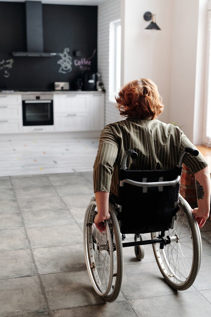 Home Woman in wheelchair moving around a modern kitchen, showcasing independence and domestic life.