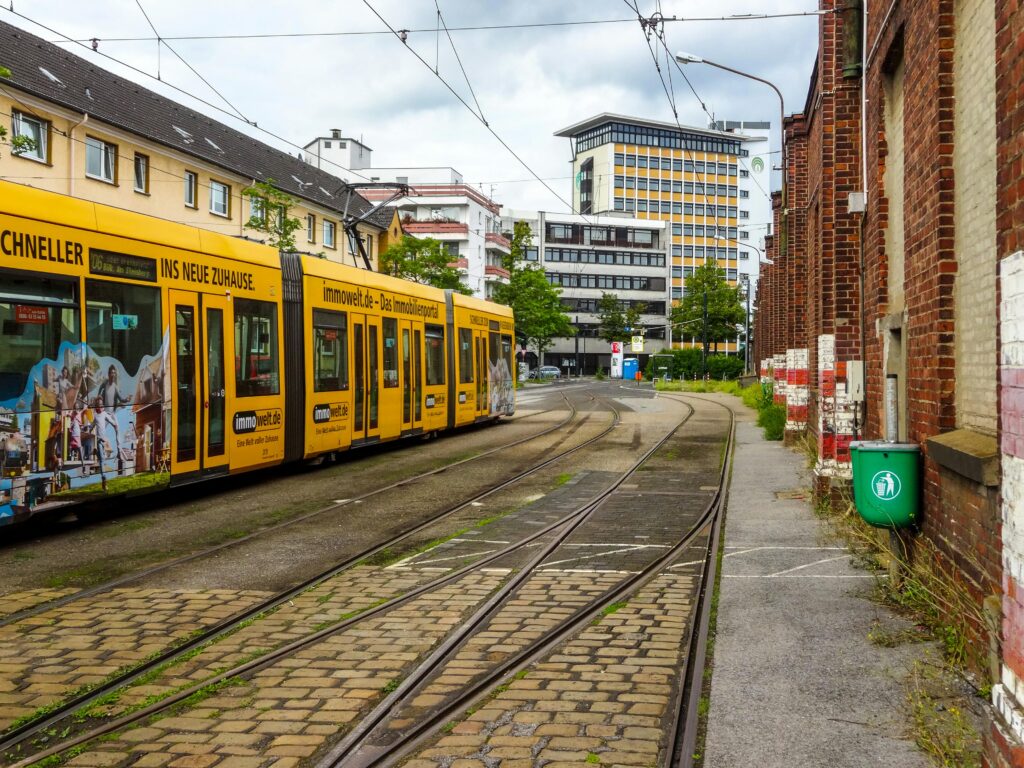 pexels photo 7018454 7018454 Colorful yellow tram in downtown Düsseldorf, showcasing urban architecture and vibrant city life.