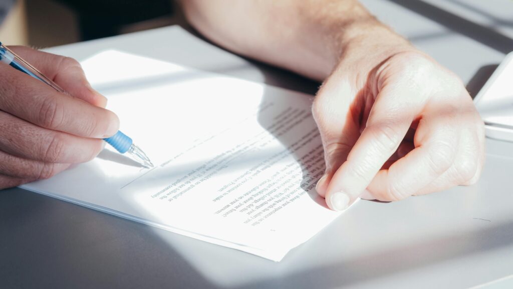 pexels photo 7054502 7054502 Hands signing a contract with a blue pen, close-up view.